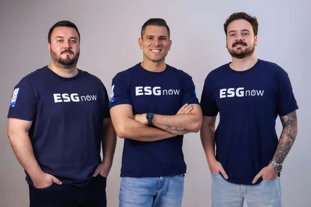 Três homens usando camisetas azul escuro com a frase 'ESG now' em destaque, representando uma equipe que oferece ferramentas de ESG para empresas.
